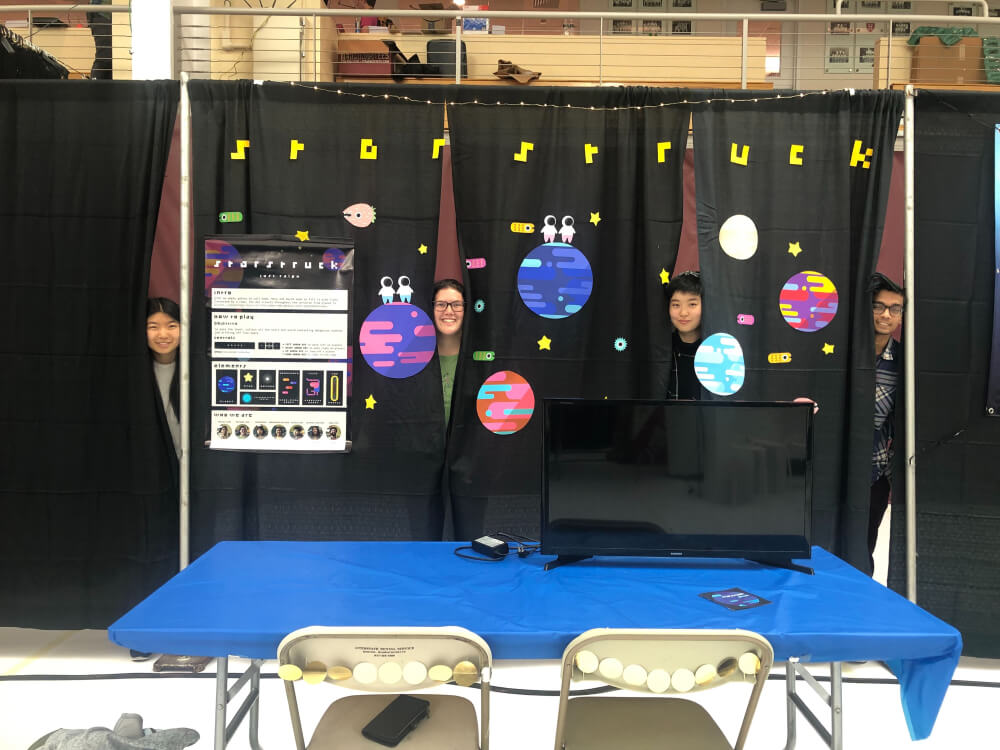 my teammates poking their heads out from behind the curtains at our BostonFIG booth